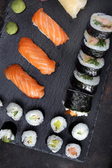 Sushi. .Apetyczne, różnorodne sushi na kamiennym talerzu. Kompozycja na ciemnym tle. - obrazy, fototapety, plakaty