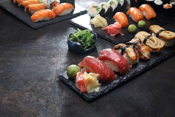 Zestaw sushi. Apetyczne, różnorodne sushi na kamiennym talerzu. Kompozycja na ciemnym tle. - obrazy, fototapety, plakaty