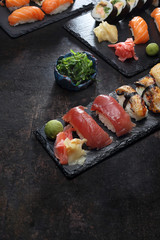 Sushi.  Apetyczne, różnorodne sushi na kamiennym talerzu. Kompozycja na ciemnym tle. - obrazy, fototapety, plakaty