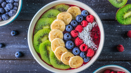 Healthy breakfast with delicious acai smoothie in bowl on dark background