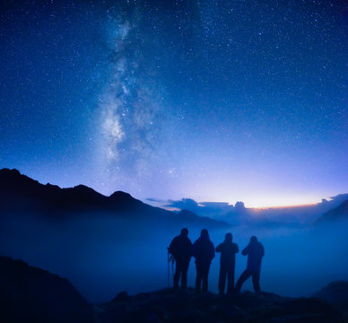 Group Of Travelers Looking At The Starry Sky In The Mountains.