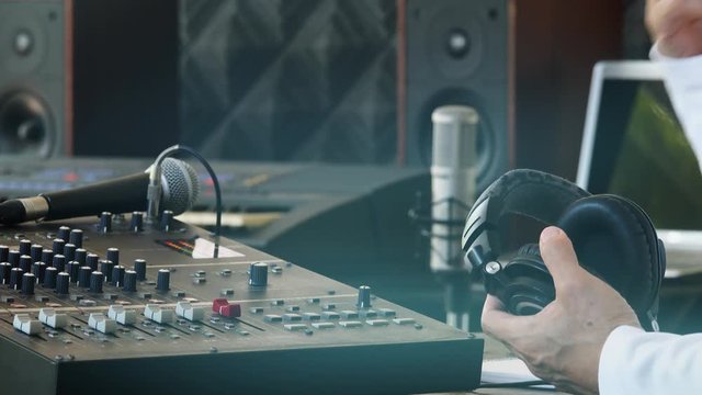 Music producer working in recording studio.
Male sound engineer producer holding headphone snapping and OK finger up to colleagues ,4K video. 
