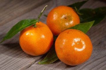 Three fresh mandarins on a rustic wooden table