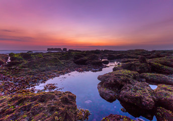Sunset as seen from Mengening Beach, Bali,Indonesia. Mossy rocks in the foreground. Vibrant Colour...