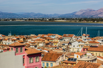 Obraz premium small south city in Mediterranean shore line waterfront view from above with shingles roof on tops and sea port bay and mountain country side horizon landscape on background 