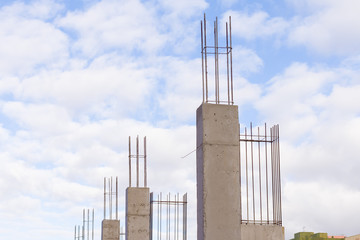 Baustelle mit gegossenen Betonstützen mit Armierungseisen vor blauem Himmel mit Wolken