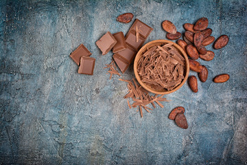 Top view of chocolate chips and pieces of bars with cocoa beans for confectionery