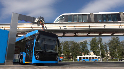 Blue electric bus at the charging station.Modern trains on the monorail.