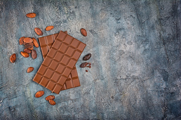 Top view of two tasty dark chocolate bars with cocoa beans