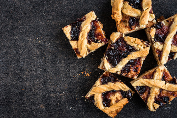 Homemade shortbread cookies with jam on black background.