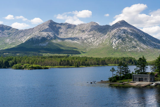 Beautiful scenery in Inagh Valley, Connemara, County Galway, Ireland with a lake at the foot of the mountains and a cabin built at the lake-shore.