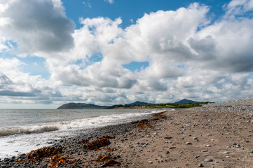 Dramatic sky over Killiney Beach in County Dublin, Ireland. Seascape with low clouds and a pebble beach on a summer day.