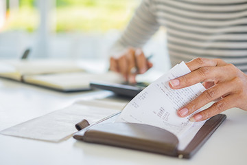 Woman with bills and calculator. Woman using calculator to calculate bills at the table in office. Calculation of costs.