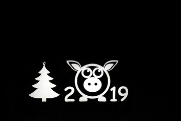 New 2019 year concept with pig and Christmas tree cutouts background white on black isolated. Copy space flat lay