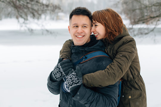 Winter portrait of young beautiful happy smiling couple outdoors. Christmas and winter holidays. Man and woman in snowy park