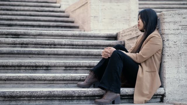 Lonely sad asian young woman sitting on stairs thinking-outdoor