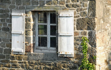 Fenêtres et volets blancs d'une maison bretonne en pierre, département de la Manche, France