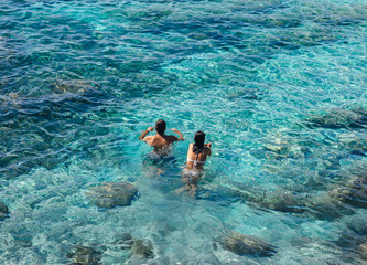 Happy couple swimming in the transparent turquoise sea.