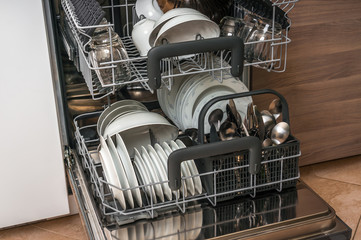 Open dishwasher with clean dishes after cleaning process