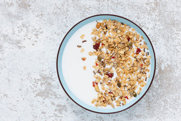 Granola, oatmeal with milk, honey and strawberry on blue plate