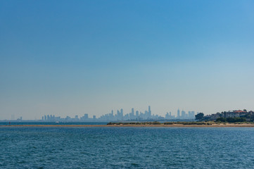 Obraz na płótnie Canvas Blue ocean with beach and cityscape on the background