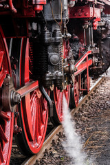 Detail of a steam locomotive with white Steam, white Steam, Detail of Big red Wheels, rod Drive of a steam locomotive