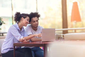 Interracial couple using tablet computer in coffee shop