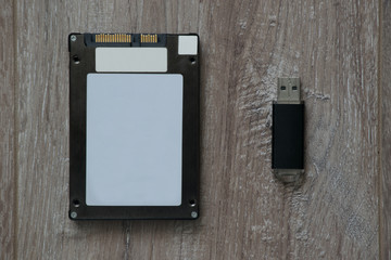 Solid State Drive (SSD) and flash drive on brown wooden background