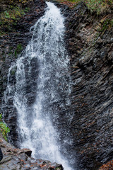 Mountain waterfall. View of the waterfall in the fall. Water flows over the mountains
