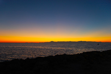 Fototapeta premium Orange-red sky after sunset and the silhouettes of the mountains. Autumn twilight.