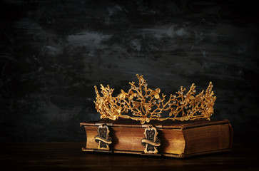 low key image of beautiful queen/king crown on old book. vintage filtered. fantasy medieval period.