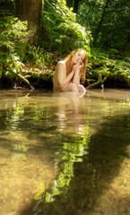 junge sexy rothharige Frau sitzt im Sommer Licht im Bach Fluss am Ufer stützt den Kopf in die Hände und träumt von der Liebe