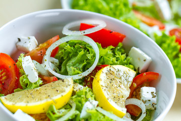 Fresh, healthy vegetable salad with feta cheese and lemon wedges in a plate. Healthy and right food. Diet
