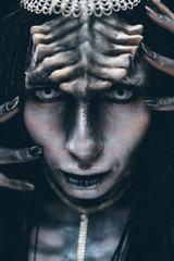 Portrait of woman in image of extraterrestrial alien with horns on her head and demonic eyes.