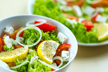 Fresh, healthy vegetable salad with feta cheese and lemon wedges in a plate. Healthy and right food. Diet