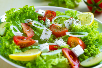 Fresh, healthy vegetable salad with feta cheese and lemon wedges in a plate. Healthy and right food. Diet