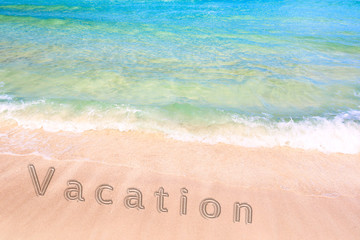 Fototapeta na wymiar Inscription of a vacation word on the sand on beautiful beach with a blue turquoise sea wave. Concept of a summer vacation and recreation