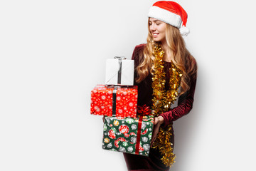 Beautiful girl in the hat of Santa Claus, in her hands a Christmas gift.