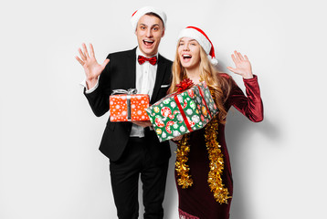 A stunned pair of lovers in Santa Claus hats celebrating the new year and giving each other...