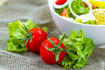 Fresh, healthy vegetable salad with lettuce, cherry tomatoes, onion, feta cheese, lemon, sprinkled with spices in a plate. Proper nutrition and right food. Diet