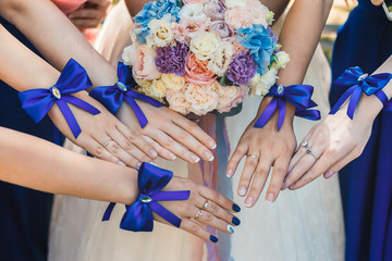 Bridesmaids stretched out their hands with blue identical bracelets in the form of bows. The...