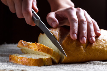 Slicing long loaf from the bakery on the table. Bakery products. Bread from rye, wheat flour