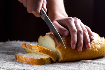 Slicing long loaf from the bakery on the table. Bakery products. Bread from rye, wheat flour