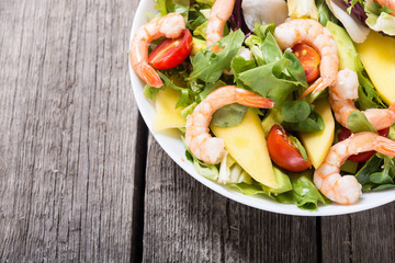 Mix of salad with shrimps , avocado and cherry tomatoes . Healthy food background
