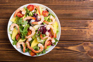 Mix of salad with shrimps , avocado and cherry tomatoes . Healthy food background