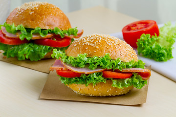 Appetizing sesame buns with fresh lettuce, tomato and ham for snack. Homemade sandwiches