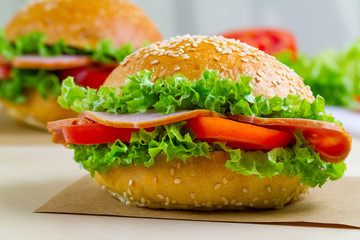 Appetizing sesame buns with fresh lettuce, tomato and ham for snack. Homemade sandwiches