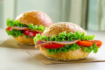 Appetizing sesame buns with fresh lettuce, tomato and ham for snack. Homemade sandwiches