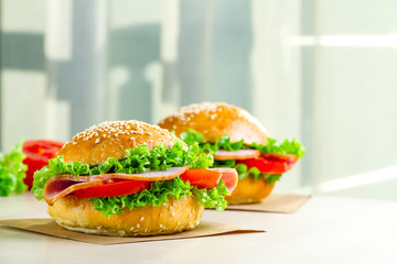 Appetizing sesame buns with fresh lettuce, tomato and ham for snack. Homemade sandwiches
