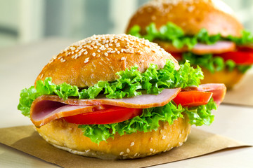 Appetizing sesame buns with fresh lettuce, tomato and ham for snack. Homemade sandwiches
